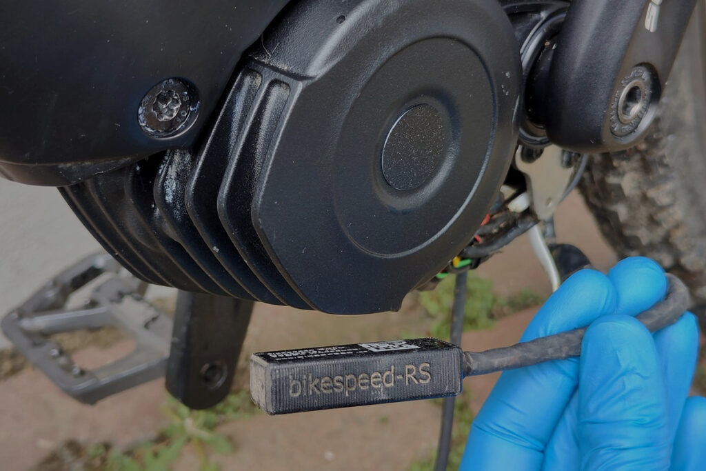 Mechanic holding a Bikespeed-RS tuning dongle next to a Bosch mid-drive motor